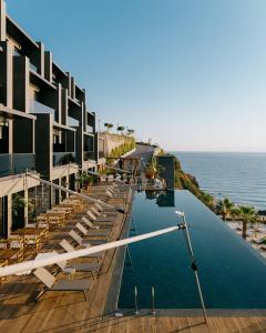 a hotel with a swimming pool next to the ocean at MGallery The Bodrum Hotel Yalikavak in Yalıkavak