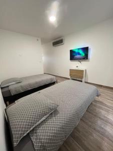 a room with two beds and a flat screen tv at Superbe appartement à 15min de Lyon in Saint-Fons