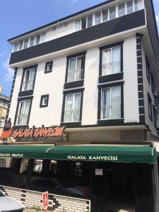 a tall white building with a green awning at Galata Apart Suite in Bostancı