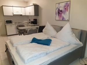 ein großes weißes Bett mit einem blauen Kissen darauf in der Unterkunft Ostseebad Sellin auf Rügen Apartment im Haus Baltic 1 OG in Ostseebad Sellin