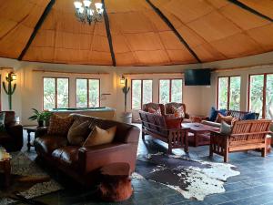 a living room with couches and tables and windows at Belvedere Game Ranch in Magudu