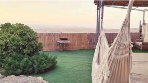 a hammock in a backyard with a fence at חלון למדבר in Arad