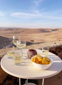 una mesa con un tazón de patatas fritas y copas de vino en חלון למדבר, en Arad