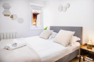 um quarto com uma cama com lençóis brancos e uma janela em Cosmo ideal famille rue Carnot em Annecy