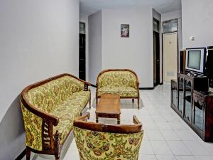 Cette chambre dispose de 2 chaises, d'une table et d'une télévision. dans l'établissement SPOT ON 92388 Villa Segi Delapan, à Prigen