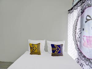 een kamer met drie kussens op een witte muur bij SPOT ON 92388 Villa Segi Delapan in Prigen