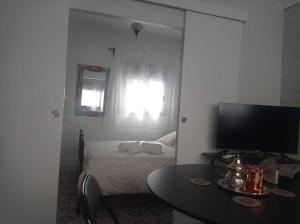 Cette chambre comprend un lit, une table et une télévision. dans l'établissement Centro de Málaga - Calle Zanca, à Malaga