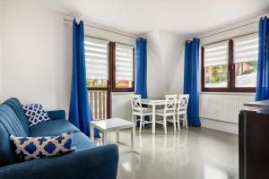 uma sala de estar com cortinas azuis e uma mesa e cadeiras em Apartamenty Wierchówka em Bukowina Tatrzańska