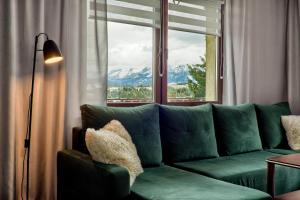 - un canapé vert dans le salon doté d'une fenêtre dans l'établissement Apartamenty Wierchówka, à Bukowina Tatrzańska