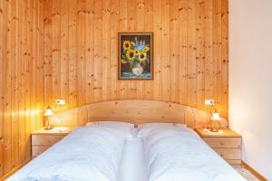 Cama en habitación de madera con 2 mesitas de noche en Adlerhorst Zaunkoenig, en Santa Valpurga