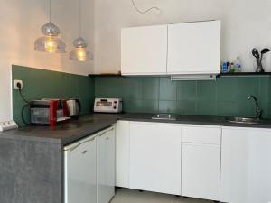 eine Küche mit weißen Schränken und grünen Wänden in der Unterkunft Apartment Olive in Medulin