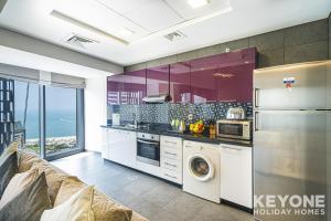 a kitchen with purple cabinets and a washer and dryer at Lavish One Bedroom with Amazing Sun Deck & Pool in Dubai