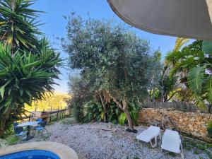 eine Terrasse mit zwei weißen Stühlen und einem Baum in der Unterkunft Exclusive Pool with your own views with 3 bedrooms and 4 bathrooms in Gozo in Għajn il-Kbira