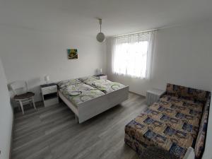 um quarto com 2 camas, uma cadeira e uma janela em Ubytovanie pre Vás em Poprad