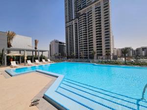 杜拜的住宿－Vacay Lettings - Getaway home Dubai Creek Harbour，一座带椅子的大型游泳池和一座高高的建筑
