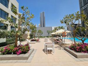een patio met tafels en stoelen en een zwembad bij Vacay Lettings - Getaway home Dubai Creek Harbour in Dubai