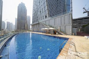 a large swimming pool in a city with tall buildings at Lavish One Bedroom with Amazing Sun Deck & Pool in Dubai