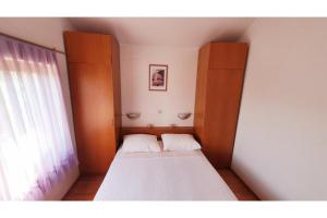 ein kleines Bett in einem Zimmer mit Fenster in der Unterkunft Apartments Villa Višnja in Pašman