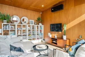 a living room with a white couch and a tv at Beachside Sanctuary - Otaki Beach Holiday Home in Otaki Beach