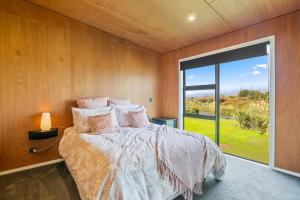 a bedroom with a bed and a large window at Beachside Sanctuary - Otaki Beach Holiday Home in Otaki Beach