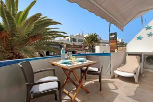ein Tisch und Stühle auf einem Balkon mit Palmen in der Unterkunft Beach Apartment Corralejo Escape in Corralejo