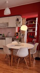 a table and chairs in a kitchen with a red wall at Stella Apartment Šibenik Charm&history united in Šibenik