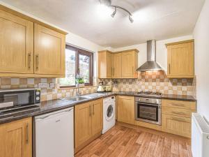 eine Küche mit Holzschränken und weißen Geräten in der Unterkunft Belle Cottage in Ashbourne + 15 Fotos