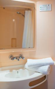 La salle de bains est pourvue d'un lavabo, d'un miroir et de serviettes. dans l'établissement Hotel Cerise Nancy, à Nancy