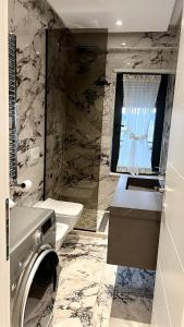łazienka z umywalką i pralką w obiekcie Zeus Tirana Suite Deluxe w Tiranie
