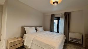 sypialnia z białym łóżkiem i oknem w obiekcie Zeus Tirana Suite Deluxe w Tiranie
