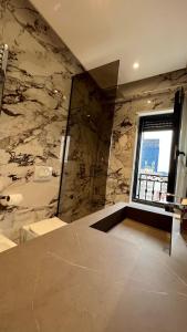 Łazienka z marmurową ścianą i oknem w obiekcie Zeus Tirana Suite Deluxe w Tiranie