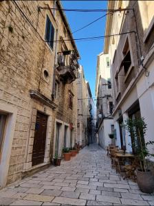 an alley in an old city with tables and buildings at Stella Apartment Šibenik Charm&history united in Šibenik