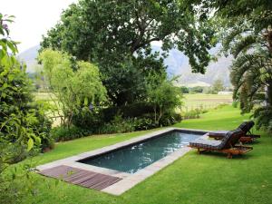 een zwembad in een tuin met een bankje ernaast bij Arumvale Country Retreat in Swellendam