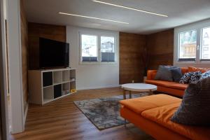a living room with an orange couch and a flat screen tv at Rosenheim in Saas-Grund