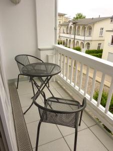 una mesa y una silla en un balcón con ventana en Ostseebad Sellin auf Rügen Apartment im Haus Baltic 1 OG en Ostseebad Sellin