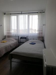 a bedroom with two beds and a window with curtains at Bridge Apartments Klaipeda in Klaipėda