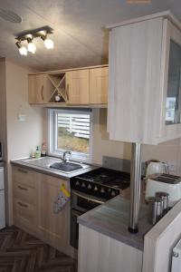 a small kitchen with a stove and a sink at Tim's Getaways Super Caravan A2, Todber Valley Caravan Park in Gisburn