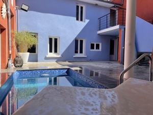 une piscine en face d'un bâtiment bleu dans l'établissement Villa Kiara Hébergements, à Cusset