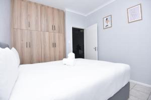 a bedroom with a white bed and a wooden cabinet at Comfy Hatfield Appartment in Pretoria