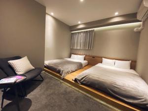 福岡市にあるTABISAI HOTEL Grande 博多のベッド2台と椅子が備わる客室です。