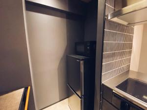 uma pequena cozinha com frigorífico e micro-ondas em TABISAI HOTEL Grande 博多 em Fukuoka