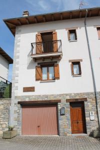 a white building with a balcony and two garage doors at Casa Rural Anie in Isaba