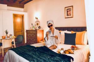 a woman sitting on a bed taking a picture at La Mandorla studio apartment in Piazza del Duomo in Florence