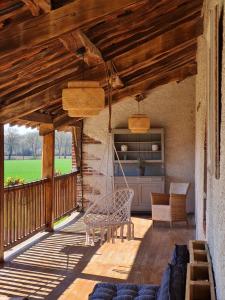 um alpendre com um baloiço, uma mesa e cadeiras em Domaine du Cuiset -Gîte des Combles em Saint-André-sur-Vieux-Jonc