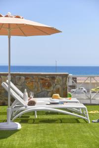 un tavolo bianco con un ombrello e un gatto che ci dorme sopra di Chalet Santa Ana 25 by VillaGranCanaria a Playa del Ingles
