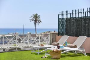 two chairs and a table on a lawn with the beach at Chalet Santa Ana 25 by VillaGranCanaria in Playa del Ingles
