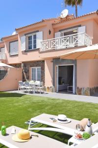 una casa con un cortile verde con tavoli e sedie di Chalet Santa Ana 25 by VillaGranCanaria a Playa del Ingles