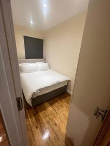 um pequeno quarto com uma cama com lençóis brancos e almofadas em 2 Bedroom Apartment,Chester Road N17 em Londres