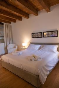 a bedroom with a large white bed with a chair at Le Maree Deluxe Apartment by Dimore Trinacria in Siracusa