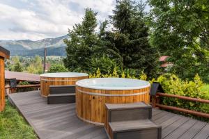 una bañera de hidromasaje en una terraza con 2 bancos en Tatra Resort & SPA, en Kościelisko